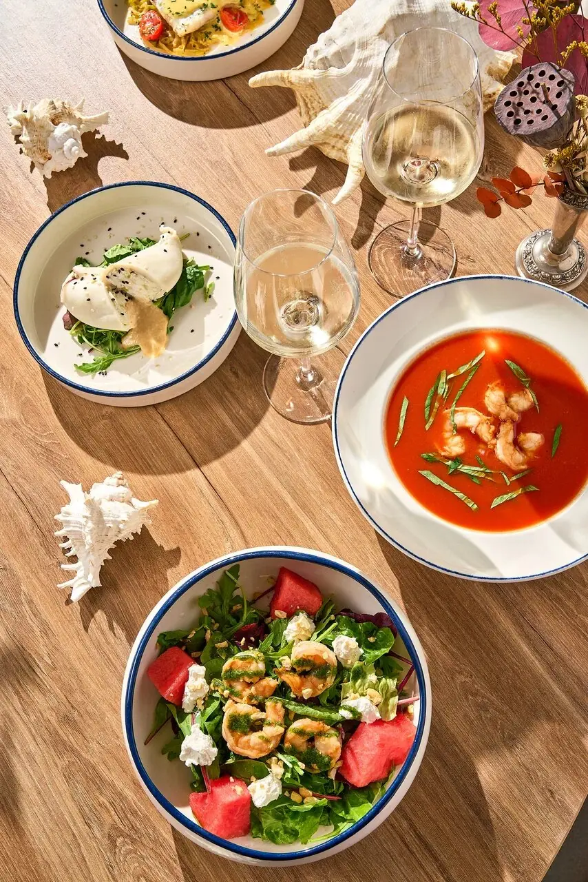 A table set with soup, salads and wine, seen from above